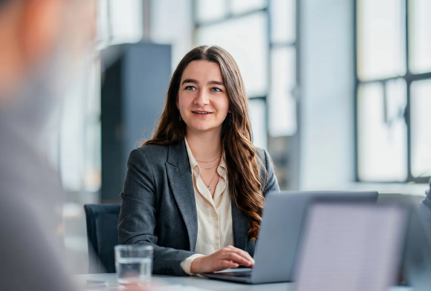 An employee works attentively on a laptop while discussing a task in a modern office – structured planning and professional project work.