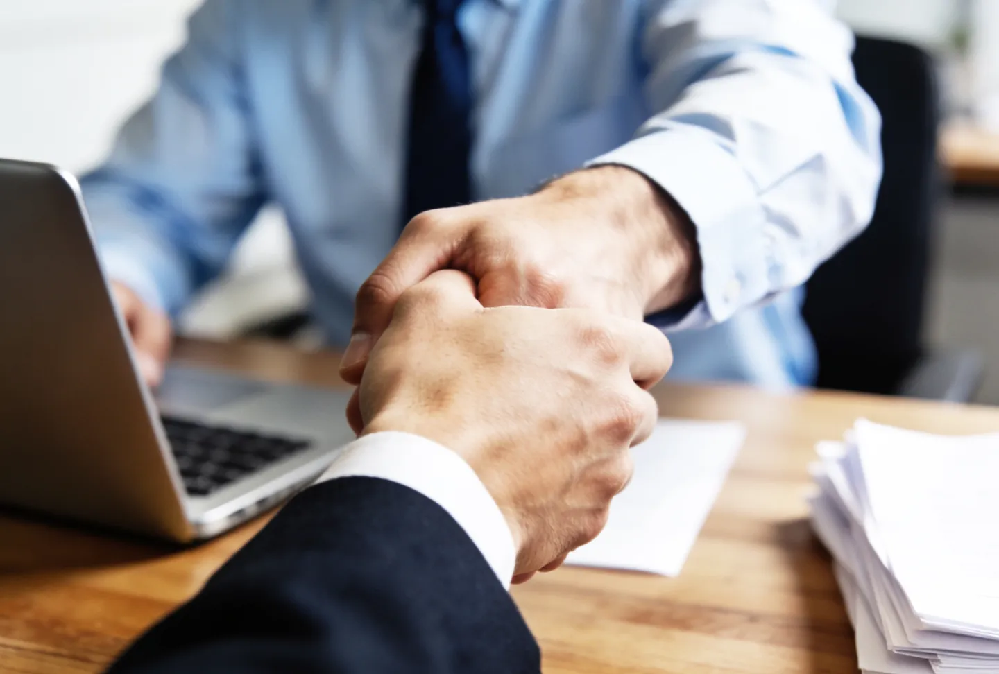 Business partners seal their collaboration with a handshake at a desk – professional cooperation and successful sales.